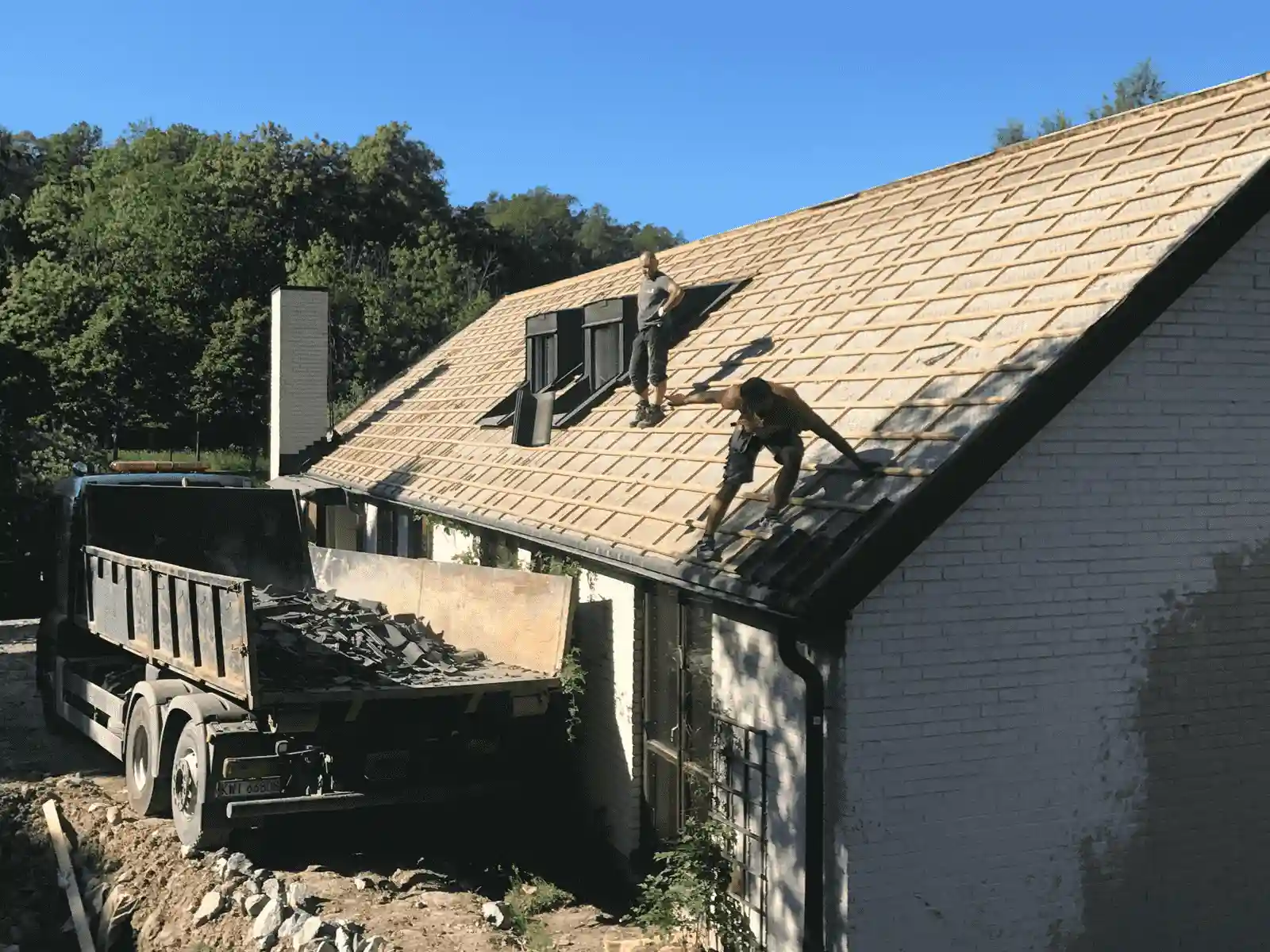 ett byggföretag river ett hus genom att ta bort takpannorna och lasta dem på en lastbil ett byggföretag river ett hus genom att ta bort takpannorna och lasta dem på en lastbil